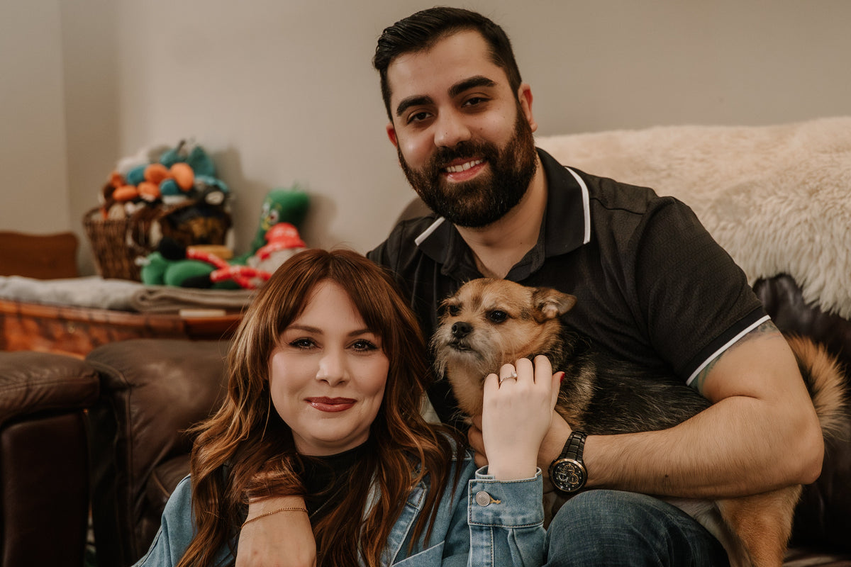 Man and woman sitting on a couch with a dog in a cozy living room.