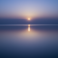 Soft glowing light reflecting on calm water in indigo and lavender tones